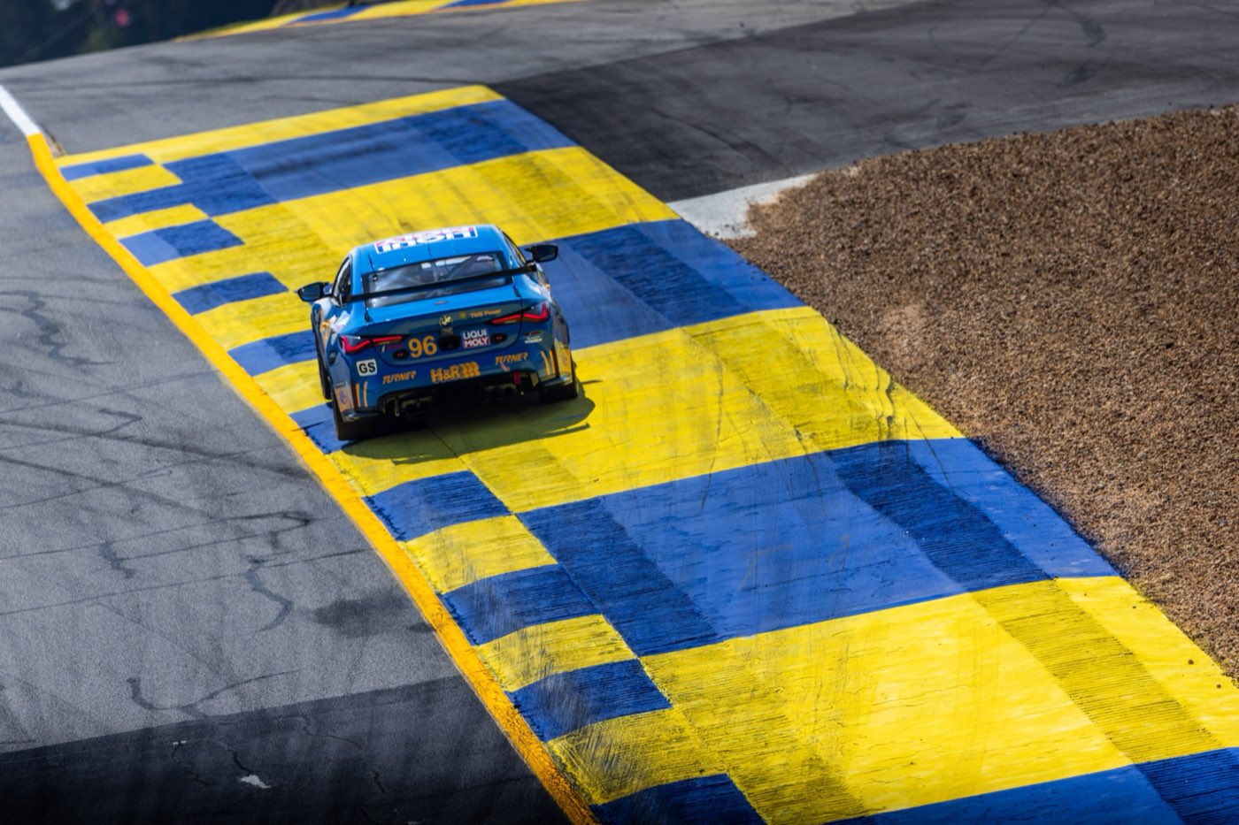 The #96 Turner Motorsport BMW M4 GT4 over the curbing at Road Atlanta